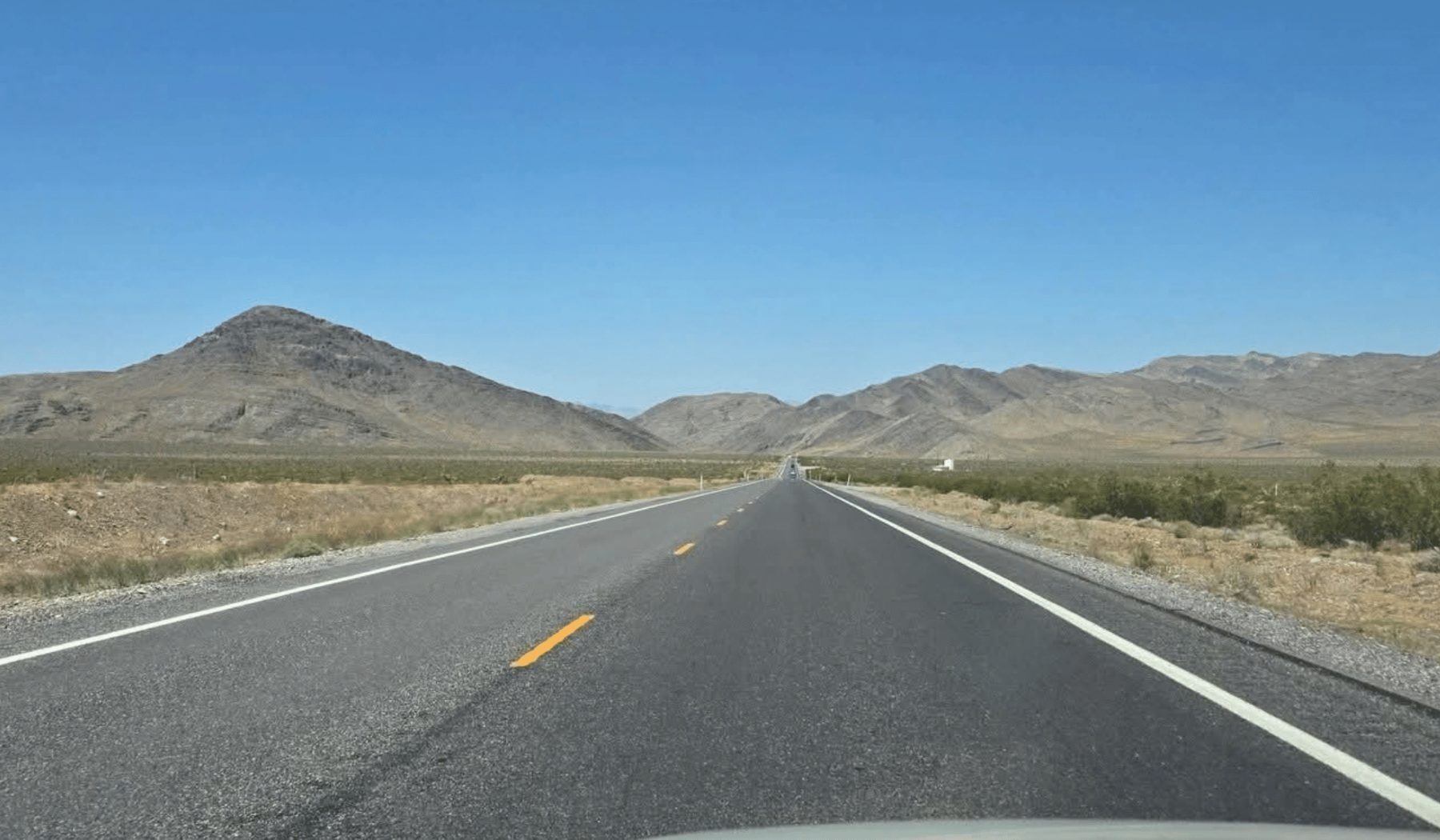 An open desert highway running toward distant mountains
